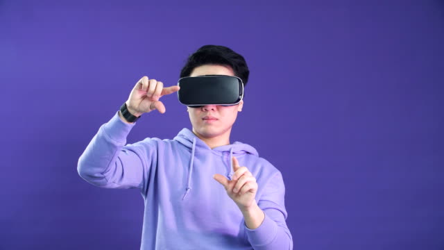 Junger-Asiener-spielt-VR-Spiel-in-dunkelblauem-Hintergrund.-Chinesischer-junger-Hipster-trägt-VR-Headset