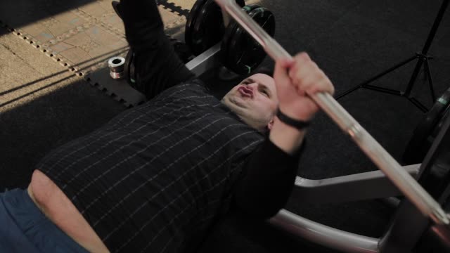 Cheerful-fat-man-performs-the-wrong-bench-press-in-the-gym