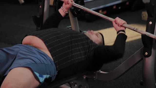 Cheerful-fat-man-performs-the-wrong-bench-press-in-the-gym