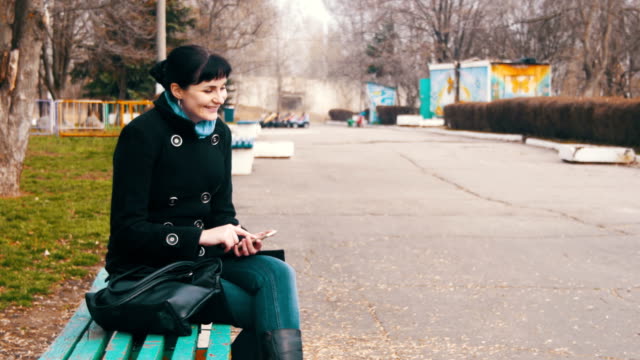 Young-Woman-using-a-Smartphone-on-a-Bench-in-the-City-Park