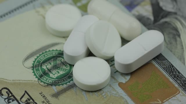 Medical-pills-and-tablets-on-dollar-banknote.-Pharmaceutical-business-concept