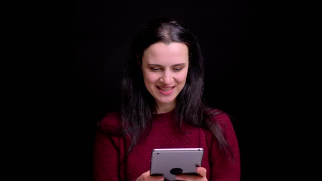Closeup-portrait-of-young-caucasian-female-with-black-hair-using-the-tablet-and-laughing-with-excitement