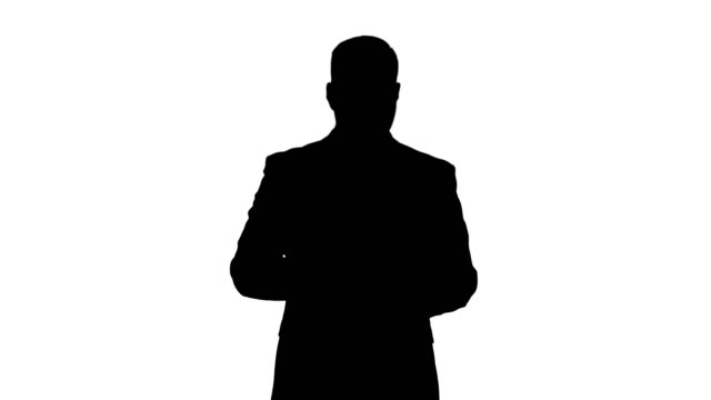 Silhouette-Businessman-walking-and-swiping-pages-on-his-tablet-computer-and-looking-to-camera-presenting-something