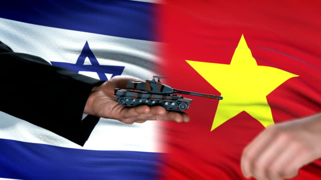 Israel-and-Vietnam-officials-exchanging-tank-money,-flag-background,-partnership