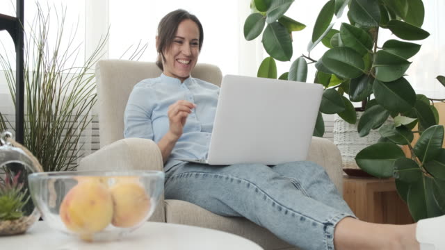 Mujer-sonriente-usando-computadora-portátil-en-casa
