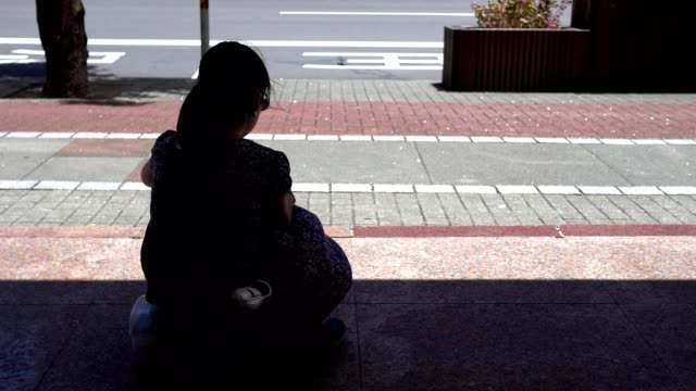 Silhouette-eines-kleinen-Mädchens,-das-an-der-Bushaltestelle-sitzt.