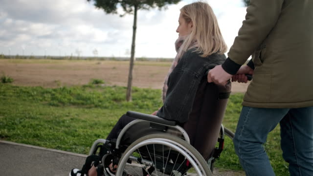 Mann-zu-Fuß-mit-behinderten-Mädchen-im-Rollstuhl