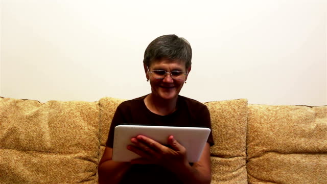 Attractive-adult-woman-working-on-her-tablet-while-sitting-on-a-sofa-at-home.