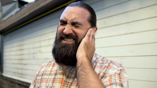 Bearded-man-rubbing-ear-to-relieve-pain,-infection-symptom,-ruptured-eardrum