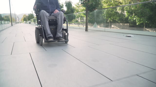4k-de-resolución-de-primer-plano-sigue-desde-delante-de-un-hombre-en-silla-de-ruedas-eléctrica-que-conduce-en-una-calle.-Concepto-de-accesibilidad