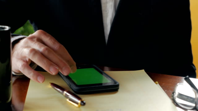 Empresario-usando-teléfono-móvil-con-pantalla-verde-bebiendo-café