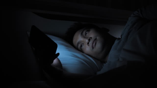Close-up-Asian-male-Using-smartphone-on-the-bed-in-home-at-night