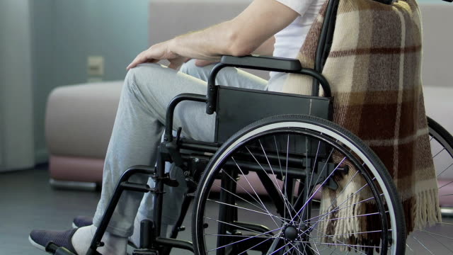 Männliche-Rollstuhl-sitzen-und-berühren-seine-Knie,-untröstlich-medizinischen-Abschluss