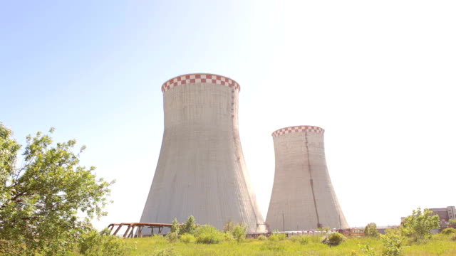 Two-cooling-towers-in-a-field-in-the-bright-sun.