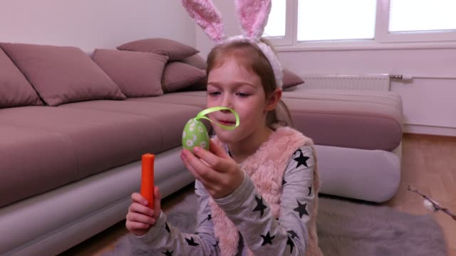 Niña-mirando-decoración-huevos-de-Pascua-y-comer-zanahoria