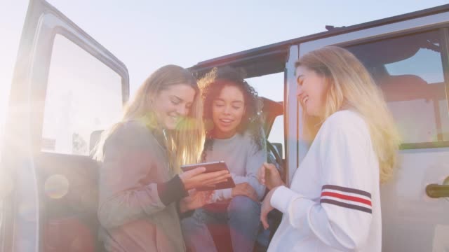 Drei-junge-Frauen-mit-Tablet-mit-ihrem-Auto-unterwegs