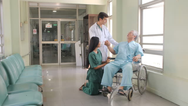 Médico-y-enfermera-tranquilizar-y-animar-a-los-pacientes-ancianos-en-silla-de-ruedas