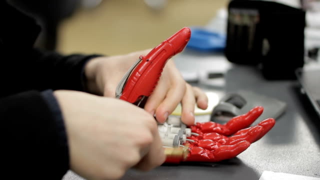 Close-up-of-young-man-assembling-bionic-hand-at-his-work-place