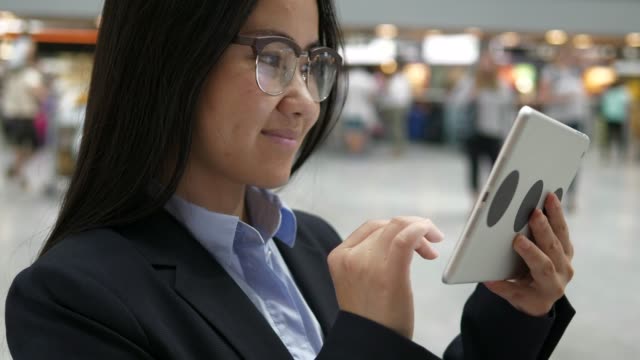Empresaria-asiática-trabajando-en-una-tableta-digital-en-el-aeropuerto