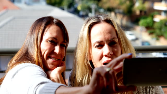 Pareja-de-lesbianas-tomando-selfie-en-la-balcón-4k