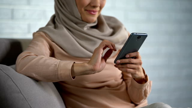 Pretty-arab-female-scrolling-smartphone-photos,-social-networks,-free-time-home