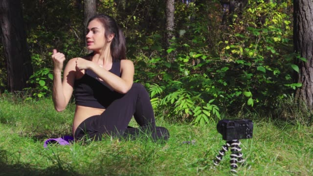 Beautiful-young-brunette-woman-shooting-workout-process-video-for-her-blog-in-a-park-with-camera