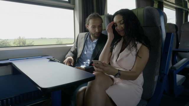 Viajeros-de-negocios-hablando-y-usando-Tablet-PC-y-smartphone-en-el-tren-entretenido-durante-el-viaje