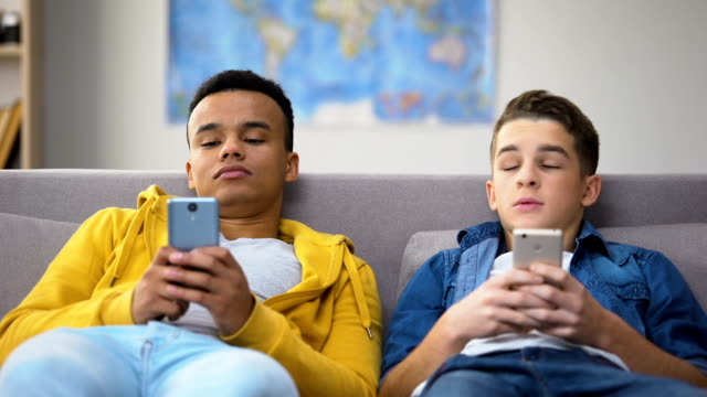 Afroamerikanische-und-kaukasische-Teenager-scrollen-Smartphones-und-haben-Freizeit