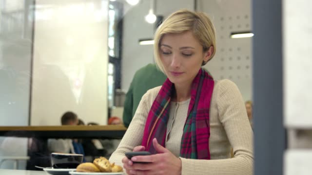 Mujer-en-Cafe-bebiendo-café-y-usando-el-teléfono-móvil
