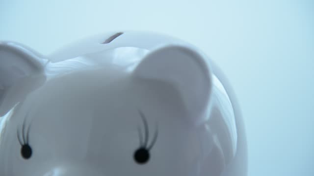 Hand-putting-coin-into-piggy-bank