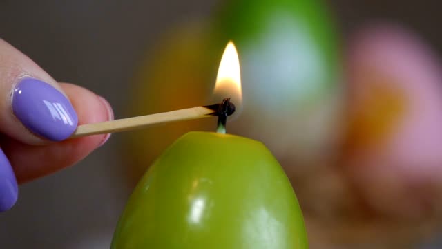 Candles-made-in-shape-of-easter-egg.-Green-candles.-Female-hand-lights-candles.