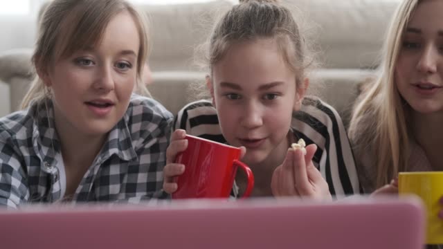 Chicas-viendo-contenido-multimedia-en-el-ordenador-portátil-mientras-que-el-café-y-palomitas-de-maíz