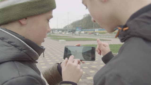 Teenage-boys-watching-skateboarding-video-on-phone