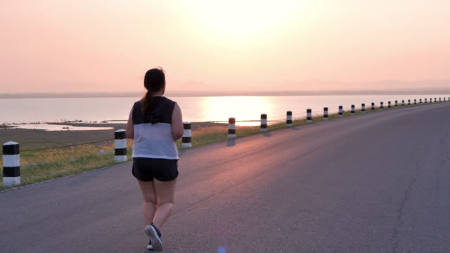 Overweight-Asian-women-jogging-in-the-street-in-the-early-morning-sunlight.-concept-of-losing-weight-with-exercise-for-health.-Slow-motion,-Rear-View