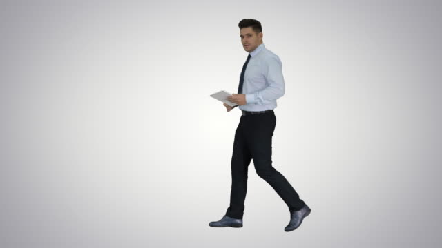 Happy-businessman-walking-in-and-using-tablet-turning-on-something-or-opening-something-on-gradient-background