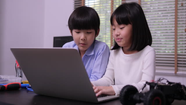 Little-girl-and-boy-using-laptop-to-working-together-at-library.-Education-and-Teachnology-concept.