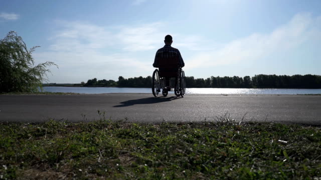 Ein-Mann-im-Rollstuhl-geht-am-Wasser-spazieren