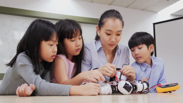 Grupo-de-Estudiantes-y-Profesores-en-clase-de-robot.-Asesor-explicar-acerca-de-su-proyecto-robot-a-estudiante.