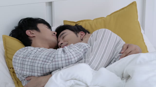 Asiatische-paar-Homosexuell-glücklich-Emotion-Morgen-im-Schlafzimmer-zu-Hause.-Homosexuell-erjunge-liegt-auf-dem-Bett-und-umarmt-Liebe-Jahrestag-zusammen.-Konzept-von-Lebensstil,-Familie,-Homosexuell-und-Bisexuell.
