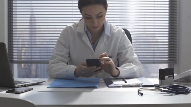 Arzt-arbeitet-im-Büro-und-benutzt-ein-Smartphone