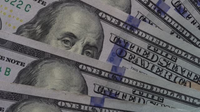 El-dinero-de-papel-rota-de-cerca.-Antecedentes-con-dinero-billetes-americanos-de-cien-dólares