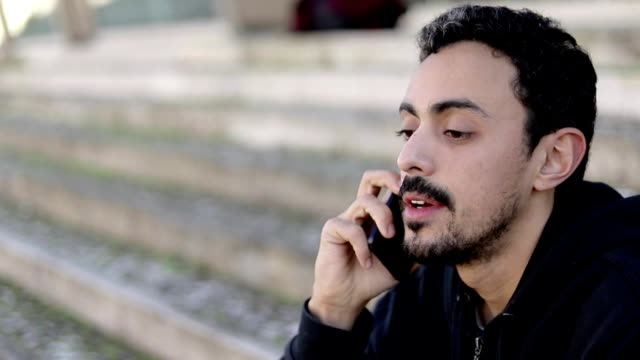 Ernster-junger-Mann-spricht-per-Smartphone