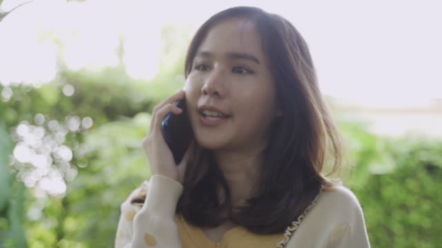 De-cerca-toma-de-imágenes-4K-de-joven-mujer-asiática-usando-móvil-con-feliz.