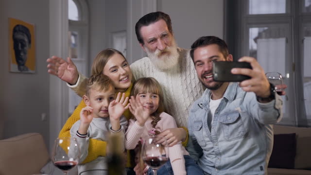 Frontansicht-der-charmanten-lachenden-Familie,-die-am-Esstisch-sitzt-und-Selfie-macht