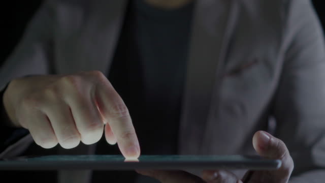 4K-Video-close-up-man-hand-in-suit-using-tablet-with-black-background.