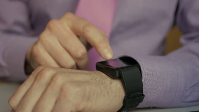 Mann-mit-seiner-Smartwatch-App.-Closeup.-Geschäftsmann-mit-trendigen-Smart-Uhren-mobile-Anwendung-auf-Touchscreen.-Guy-mit-ihrer-Smartwatch-Touchscreen-tragbare-Technologie-Gerät.-Nah.