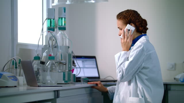 Científico-de-la-mujer-hablando-por-teléfono-en-laboratorio.-Científico-en-el-laboratorio