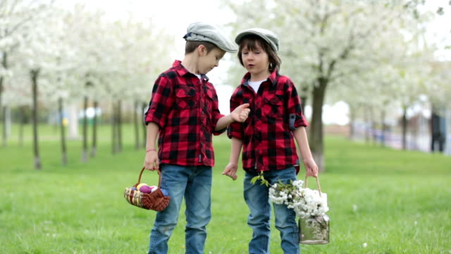 Zwei-Kinder,-junge-Brüder,-Spaß-im-Park,-schön-blühenden-Frühlingsgarten-mit-Ostereiern