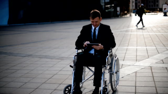 Behinderten-Geschäftsmann-sitzen-im-Rollstuhl-im-Freien-und-arbeiten-mit-Tablet-PC