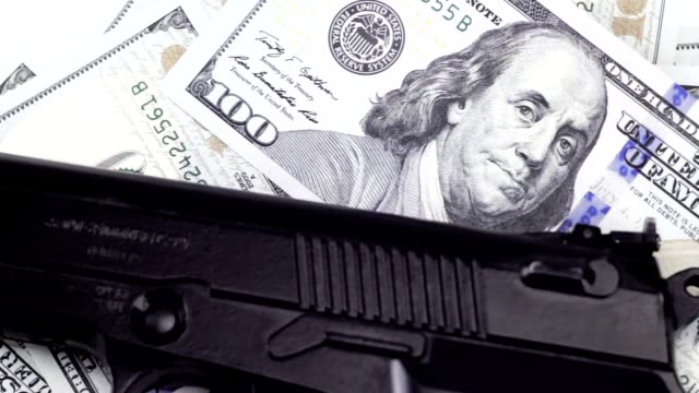 Cash-one-hundred-dollar-bills-under-the-gun,-rotating-background
